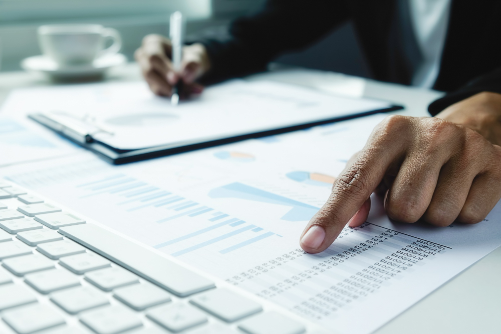 Auditor revisando estados financieros y libros contables con lupa y calculadora