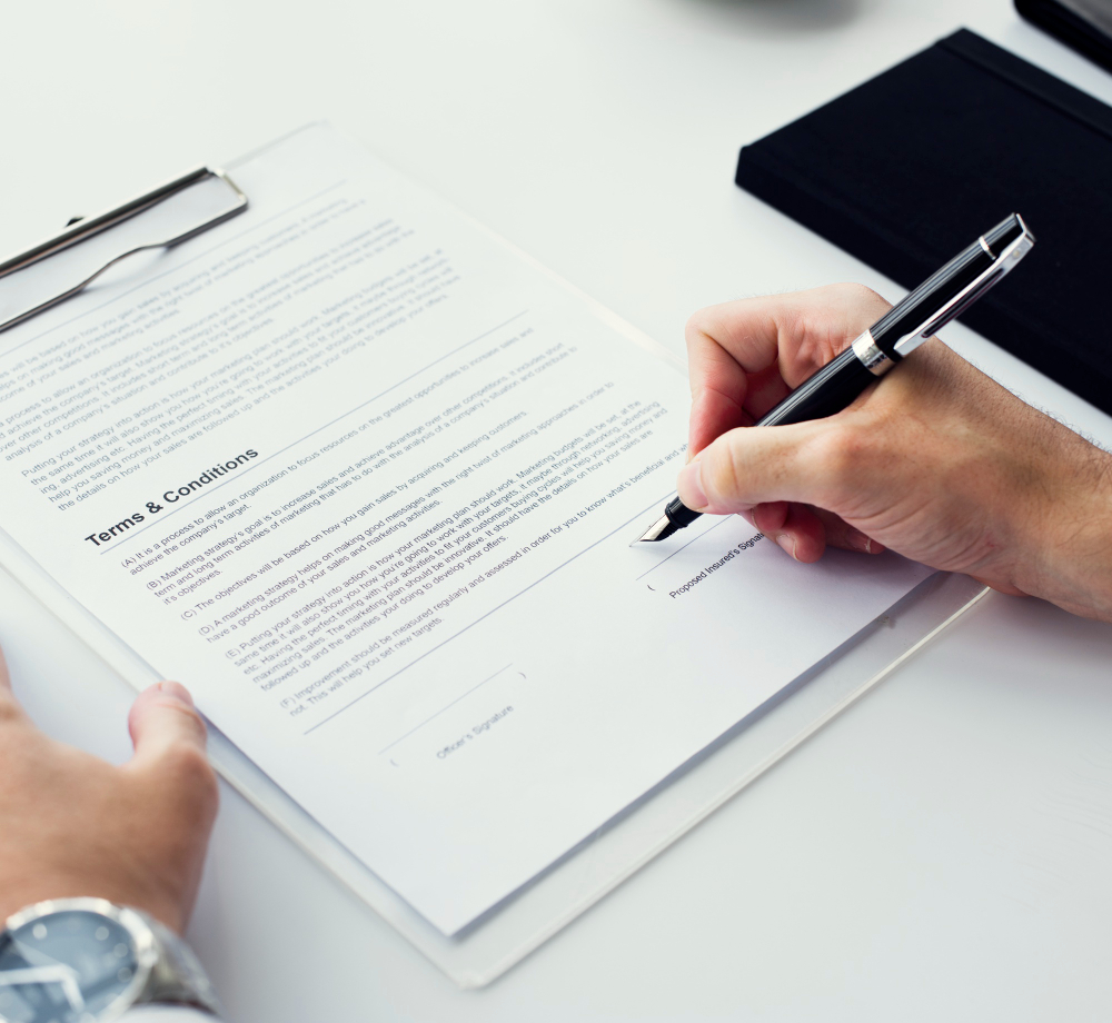 Manos firmando un contrato mercantil sobre una mesa de oficina con pluma